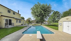 A residential setting with a swimming pool, a covered patio, and a garage.