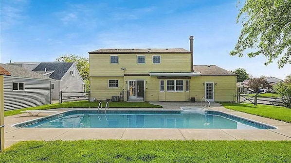 A two-story house with a swimming pool in the backyard.