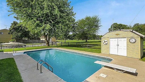 A rectangular swimming pool with a ladder, a small shed with a clock, and a tree in the background. - Cozy 1-bedroom 1-bathroom suite in enchanting Rossford with AC (Rossford)