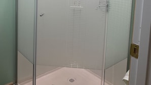 A glass-enclosed shower stall with a tiled floor and a white door. - Cozy 1-bedroom 1-bathroom suite in enchanting Rossford with AC (Rossford)