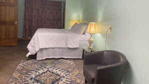 A bedroom with a bed, a chair, a lamp, a ceiling fan, and a door. - Cozy 1-bedroom 1-bathroom suite in enchanting Rossford with AC (Rossford)