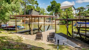 A dock with chairs, a covered area, and boats in the background.