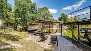 A wooden dock with chairs, a covered seating area, and a pond.