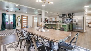 A spacious kitchen with modern appliances, a dining area with a wooden table and chairs, and a ceiling with recessed lighting.
