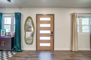 Ein Zimmer mit Holztür, einem Spiegel, einem Schreibtisch mit Lautsprecher und einem Schachbrettboden.