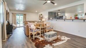 A spacious living room with a ceiling fan, a dining area with chairs, a sofa, and a cowhide rug.