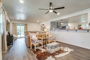 A spacious living room with a ceiling fan, a dining area with chairs, a sofa, and a cowhide rug. - Lakeside Granbury Home w/ Huge Backyard and Dock (Granbury)