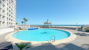 Ein kreisrunder Pool mit einer Laube, Palmen und Blick auf den Ozean.
