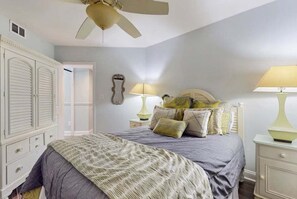 A bedroom with a bed, two bedside lamps, a ceiling fan, a wardrobe, and a door leading to another room. - Summer House 502B | Oceanfront | Pools, Hot Tub, Tennis | My Beach Getaways (Orange Beach)