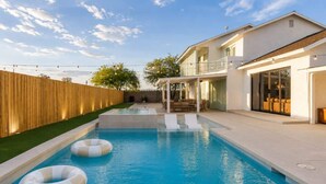 A swimming pool with inflatable rings, a wooden fence, and a house with a balcony.