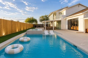 Ein Schwimmbecken mit Luftmatratzen, ein Holzzaun und ein Haus mit Balkon.
