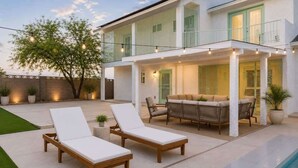 A modern house with a pool, outdoor seating, and string lights.