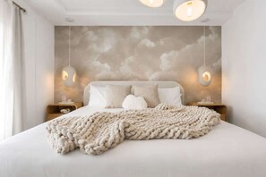 Ein Schlafzimmer mit einem Bett, einer strukturierten Wand, zwei Nachttischen und hängenden Pendelleuchten.
