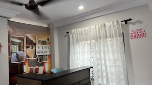 A reception desk, a ceiling fan, a reception sign with a phone number, and a wall with a poster of a hotel room. - ESTHEMERS ROYAL HOTEL (Kumasi)