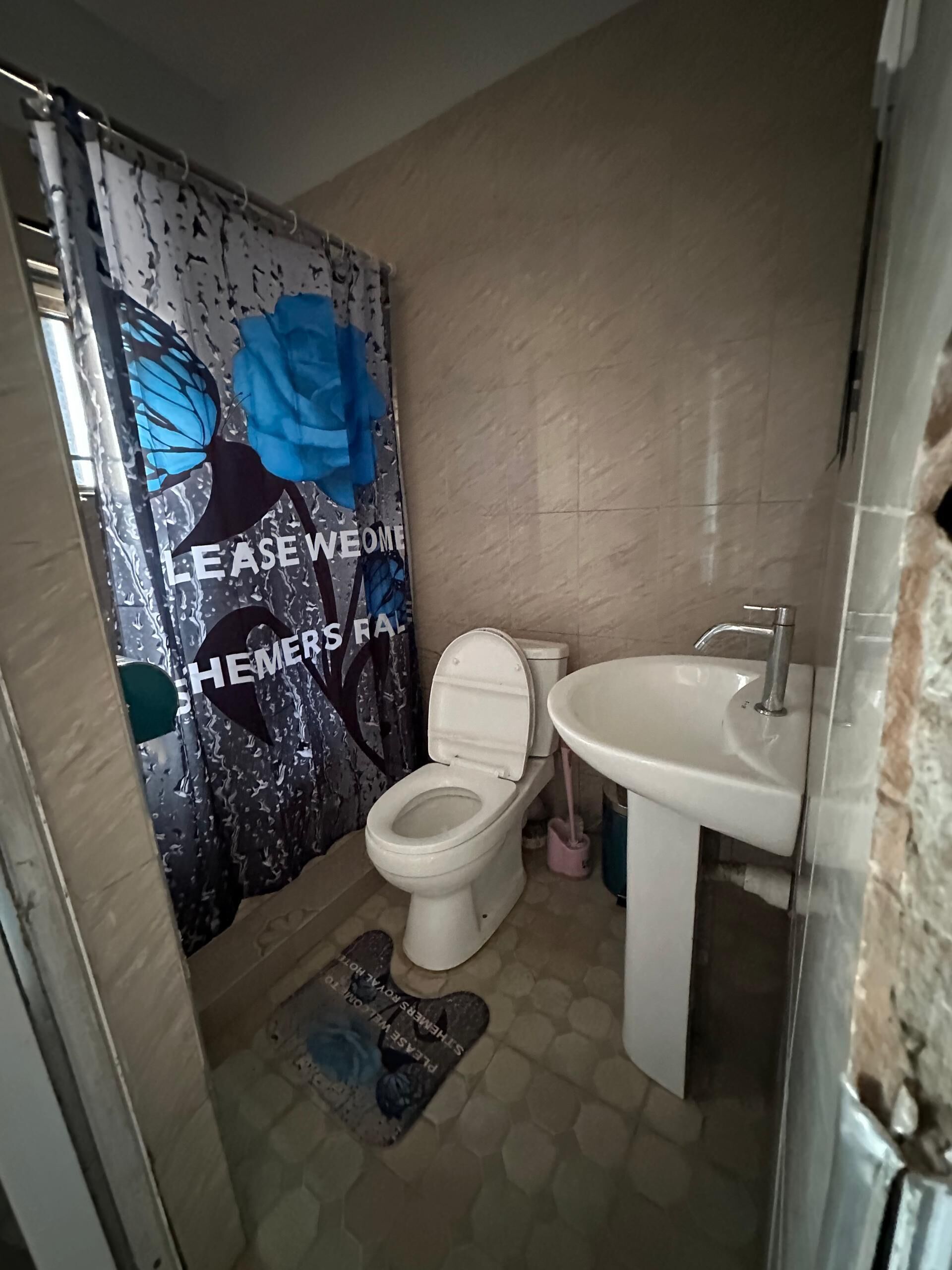 Un baño con inodoro, lavamanos y cortina de ducha con diseño floral.