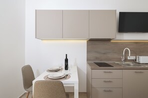 A modern kitchen with a white countertop, a built-in oven, and a wall-mounted TV. - Studio apartment Gabriella (Sukošan)