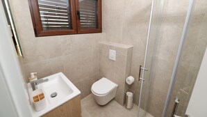 Casa de banho com lavatório, sanita e chuveiro.