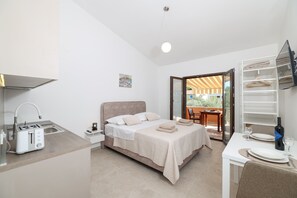 A modern hotel room with a bed, kitchenette, dining area, and a balcony with a view. - Studio apartment Antonella (Sukošan)