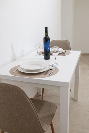 A dining table set with plates, cutlery, and a bottle of wine. - Studio apartment Antonella (Sukošan)