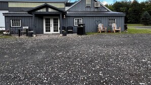 A two-story building with a gravel driveway, a front door, and two windows.