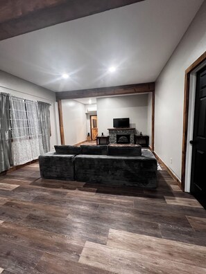 A living room with a fireplace, a television, and a seating area with cushions.