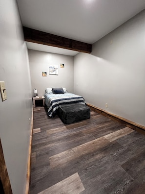 A bedroom with a bed, a nightstand, a lamp, and a small stool. - Charming 3BR Country Retreat on 5 Private Acres Near Williamstown (Williamstown)