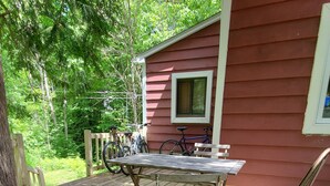 Une terrasse en bois avec une table et des chaises en métal, un vélo et un chat.