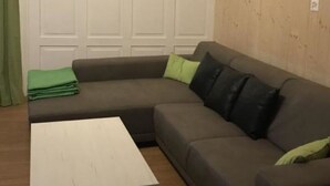 Ein Wohnzimmer mit Ecksofa, einem weißen Couchtisch und einer Holzwand.