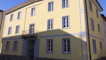 Ein gelbes Gebäude mit vielen Fenstern und einem Sockel aus Stein.