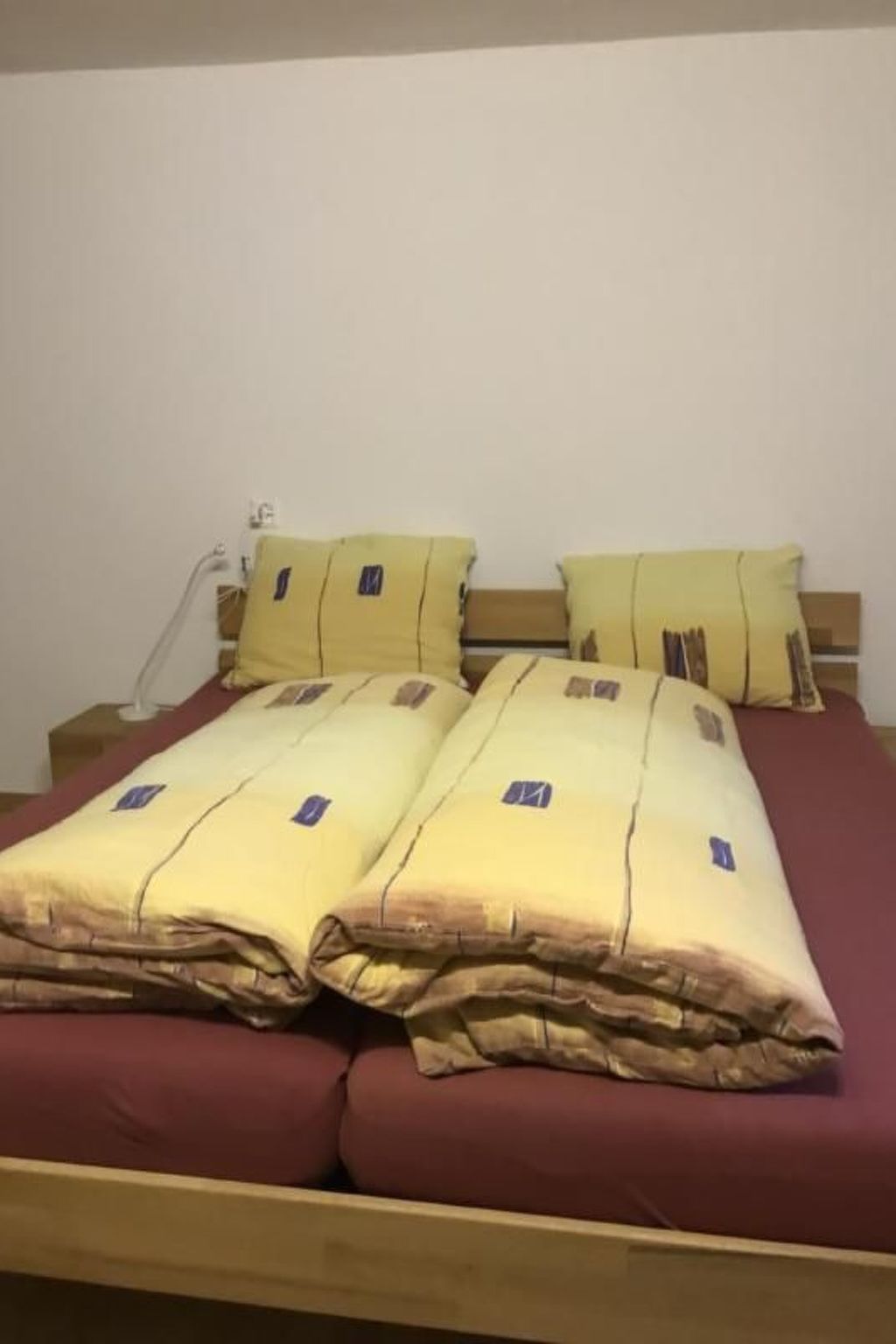 Ein Bett mit einer roten Matratze und mehreren Kissen.