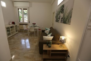 Ein Wohnzimmer mit einer Couch, einem Couchtisch, einer Lampe und einem Essbereich mit Stühlen und einem Tisch.