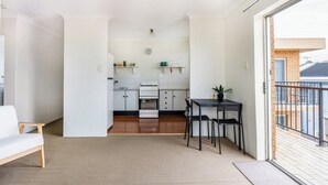 Een compacte leefruimte met een kitchenette, een eethoek en uitzicht naar buiten.