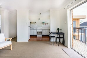 A compact living space with a kitchenette, a dining area, and a view of the outside. - Quiet and Cosy Bulimba Escape (Bulimba)