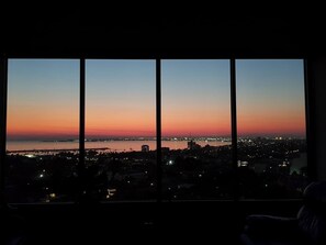 A cityscape at dusk with a view through large windows. - Soak Above the City St Kilda Rooftop Jacuzzi Stay (St Kilda)