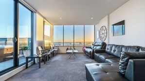 Ein modernes Wohnzimmer mit Ledersofa, Couchtisch und Blick auf die Stadt durch große Fenster.
