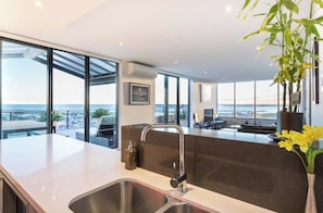 A modern kitchen with a large island, a sink, and a view of the city. - Soak Above the City St Kilda Rooftop Jacuzzi Stay (St Kilda)
