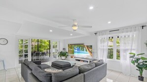 Een moderne woonkamer met een grijze modulaire bank, een flatscreen-tv en een plafondventilator.