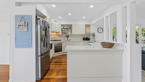 Een moderne keuken met witte kasten, roestvrijstalen apparatuur en een houten vloer.