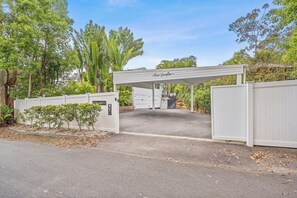 A gated entrance to a property with a covered driveway and a sign indicating 'River Champion.' - Tropical Oasis Heated Spa, Pool and Huge Decks (Ashmore)