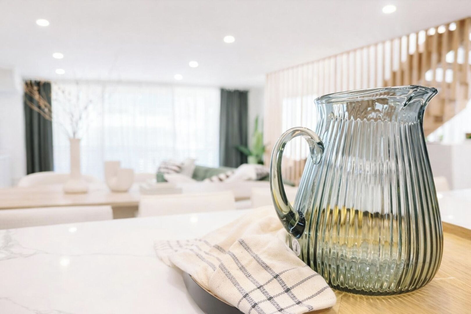 A modern living room with a glass pitcher on a table.