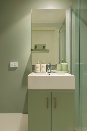 A bathroom with a mirror, sink, and toiletries. - Light and Cosy Footscray Studio | Inner-West Stay (Footscray)