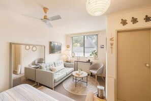 Un salon moderne comprenant un canapé, un fauteuil, une table basse et un ventilateur de plafond.