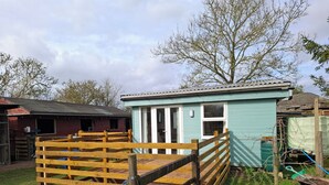 Une petite construction en bois de couleur bleu clair, avec une zone délimitée par une clôture à l’avant.