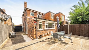 A brick house with a patio, a table, and chairs. - House Sleeps 4 - Free Parking and Garden (Manchester)