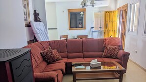 A living room with a sectional sofa, a coffee table, a small table with a remote control, and a wall-mounted mirror. - Beautiful House, Sleeps 7 With Private Pool (Iznajar)