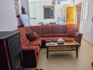 A living room with a sectional sofa, a coffee table, a small table with a remote control, and a wall-mounted mirror. - Beautiful House, Sleeps 7 With Private Pool (Iznajar)