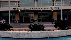 El Centro de Convenciones de Myrtle Beach con una entrada amplia, una fuente en primer plano y cielo despejado.
