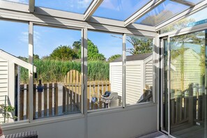 A conservatory with a view of a backyard, a wooden fence, and a grill. - Sunrise/Sunset | Affordable townhome close to Park & Carnival! (Chincoteague Island)