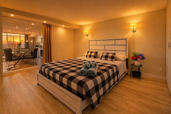 Ein Hotelzimmer mit einem Bett, einem kleinen Tisch mit Blumenvase und einem Essbereich mit Stühlen und Tisch.