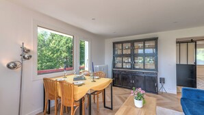 A dining area with a table and chairs, a cabinet with glass doors, a blue sofa, and a potted plant. - L'Appartement des Sommets - Welkeys (Combloux)